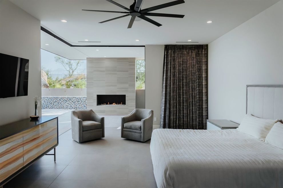 A bedroom with a bed , two chairs and a fireplace.