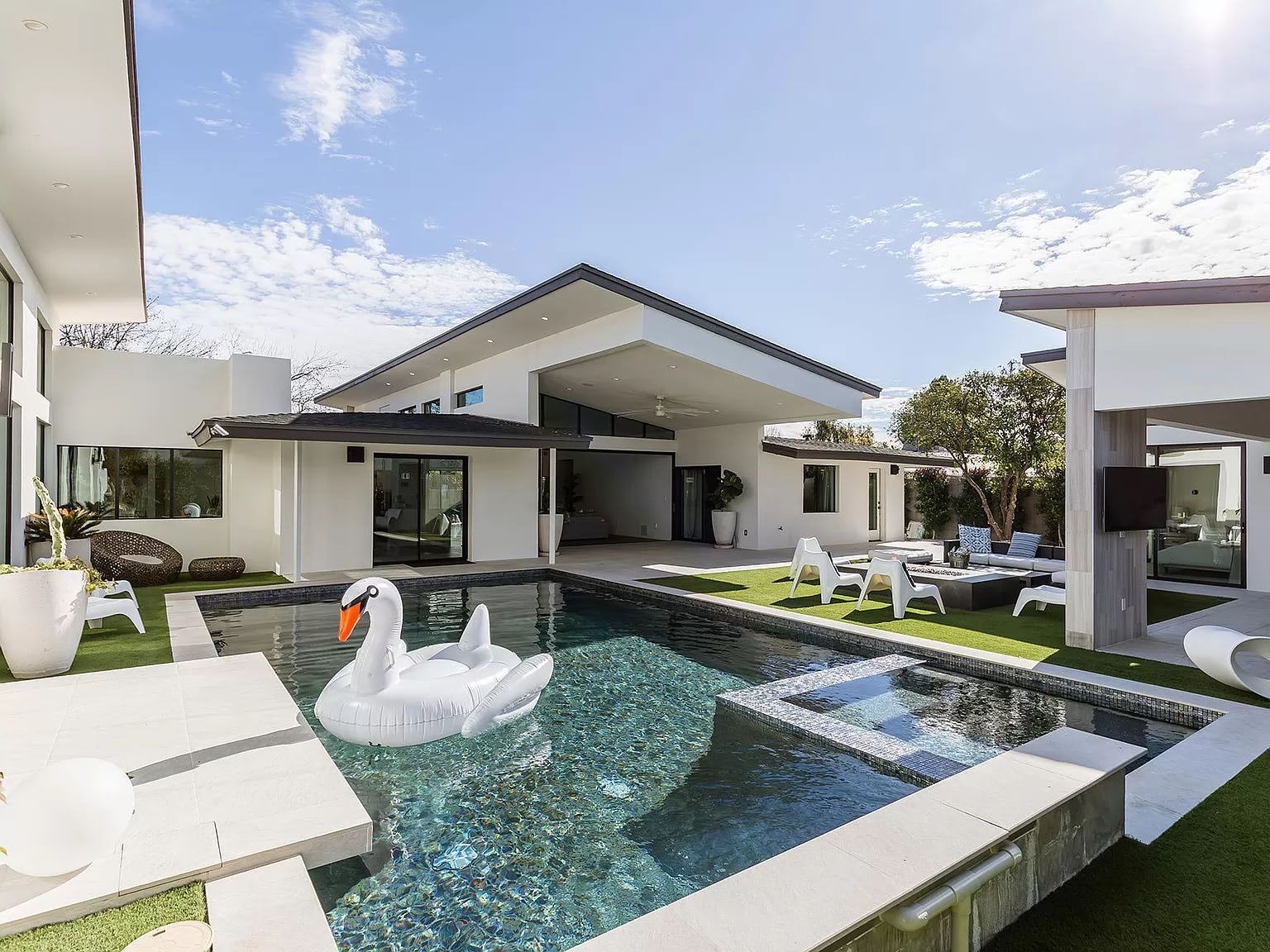 A swan float is floating in a swimming pool in front of a house in phoenix arizona