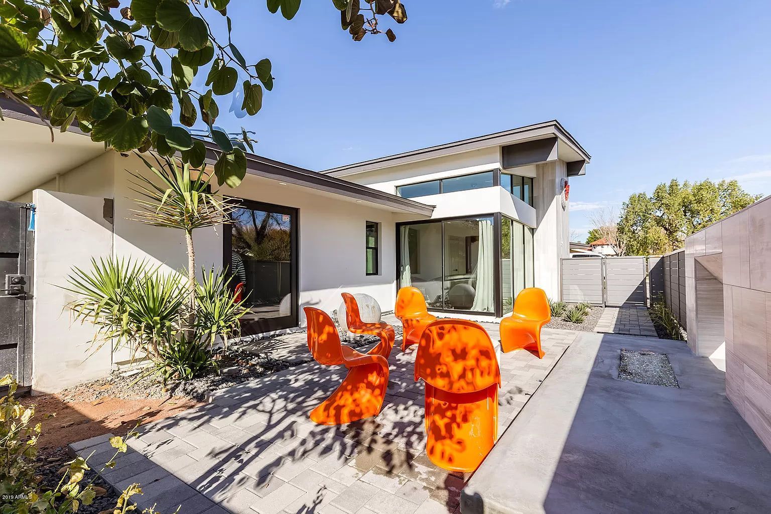 A white house with orange chairs in front of it.