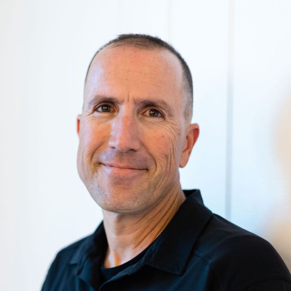 A man in a black shirt is smiling for the camera.