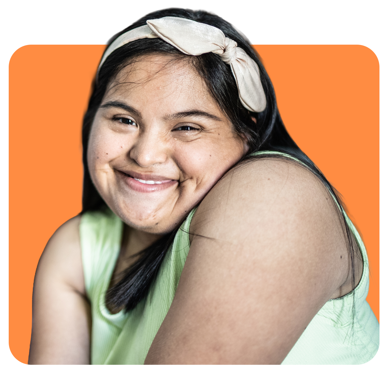 Woman with Down syndrome smiling, wearing a headband, orange background.
