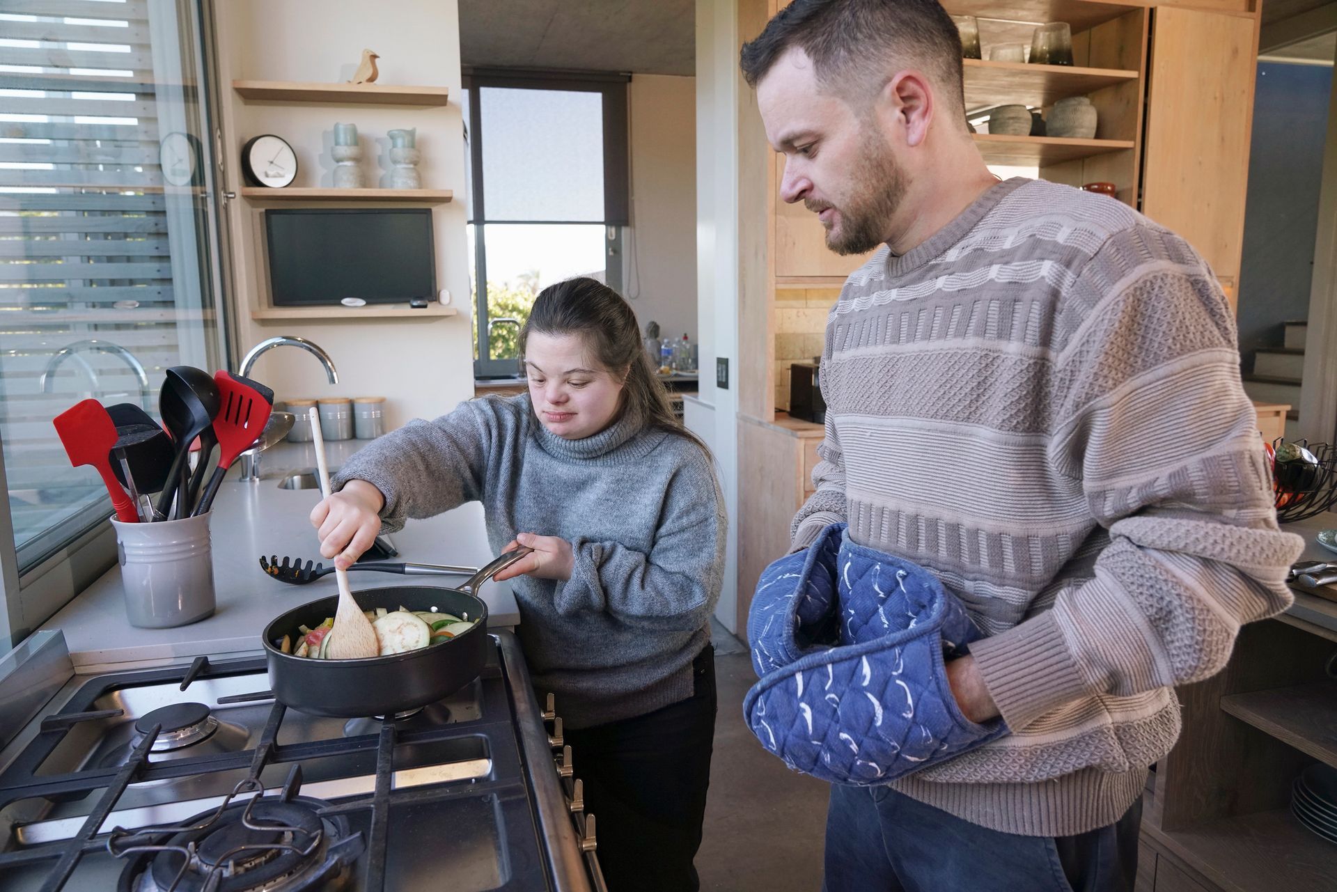 Woman with special needs cooking with assistance in a kitchen.