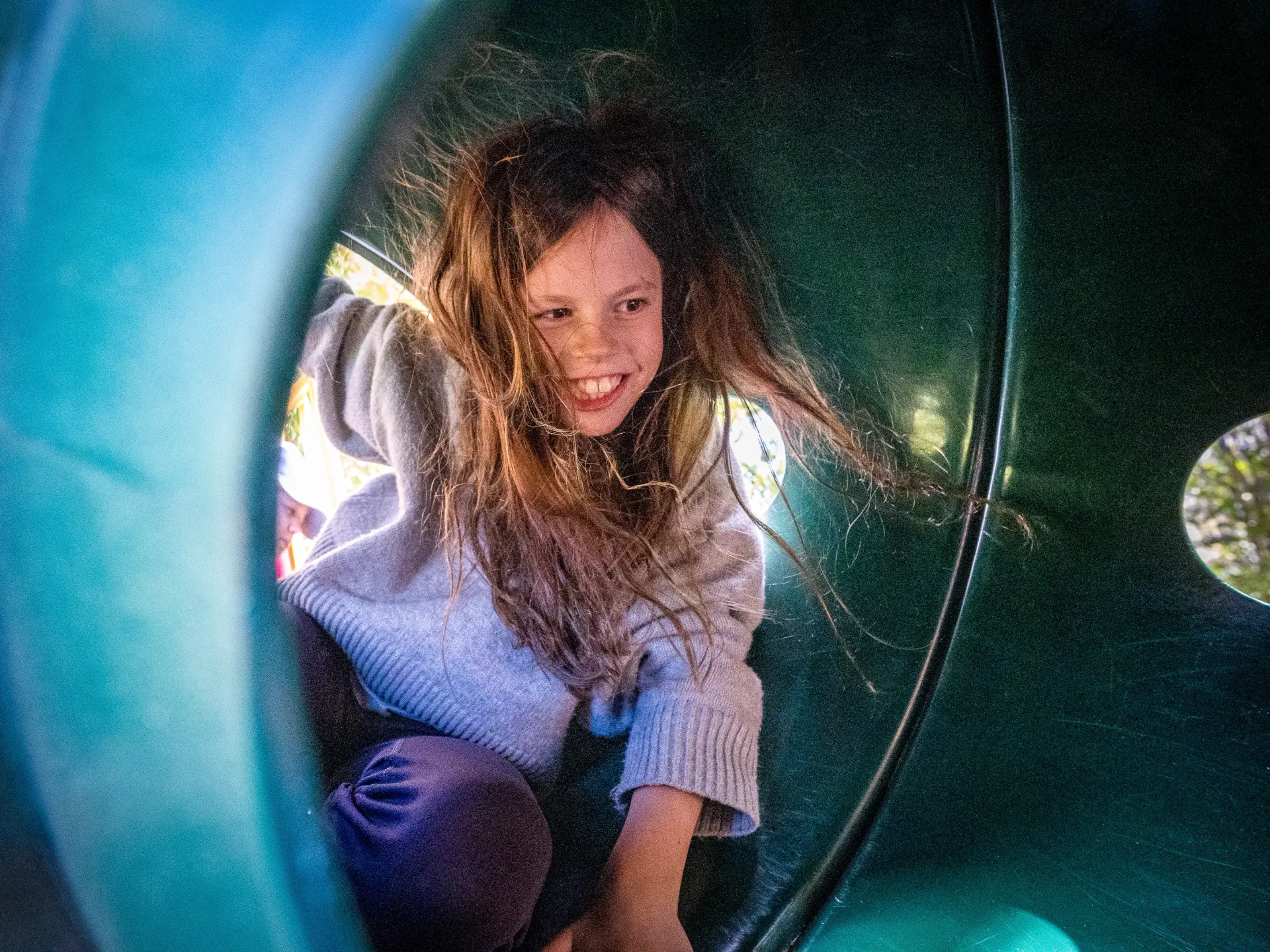Elementary student playing in a tunnel with a big smile on her face.