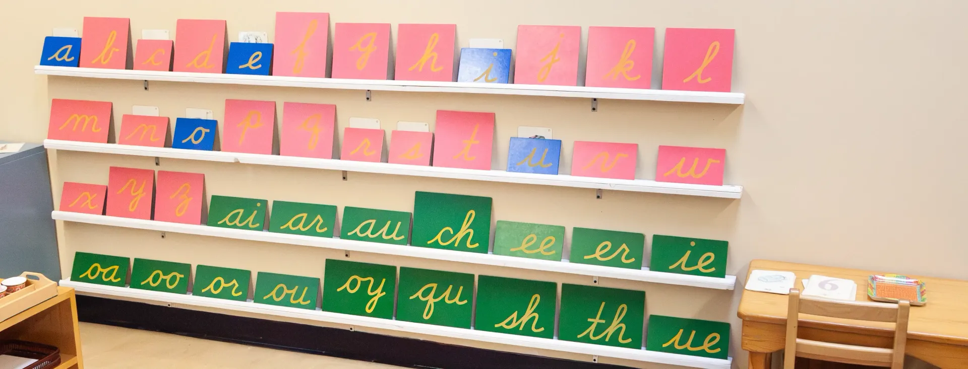 Multi-color boards with sandpaper cursive letters arranged on the wall.