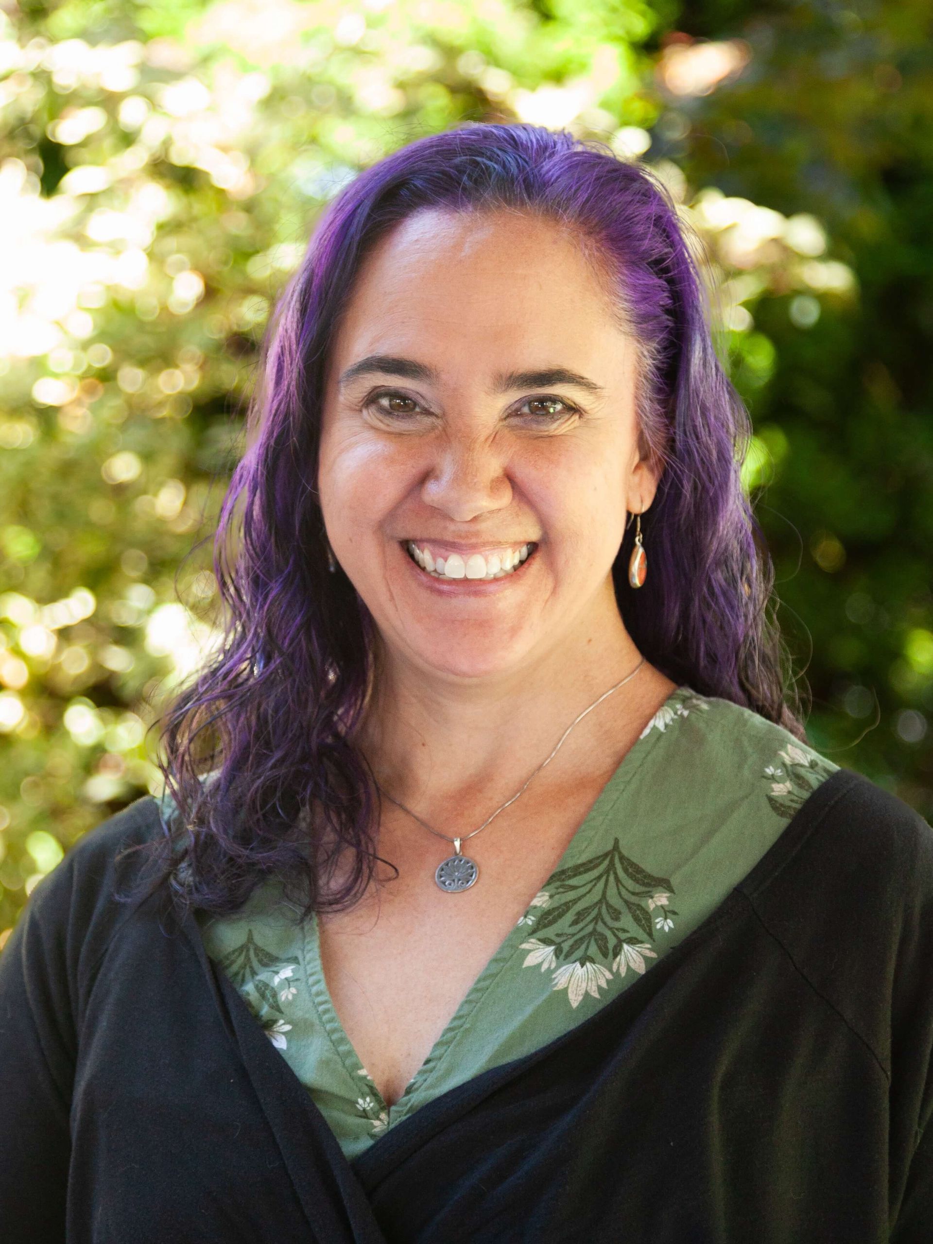 Woman with purple hair smiling.