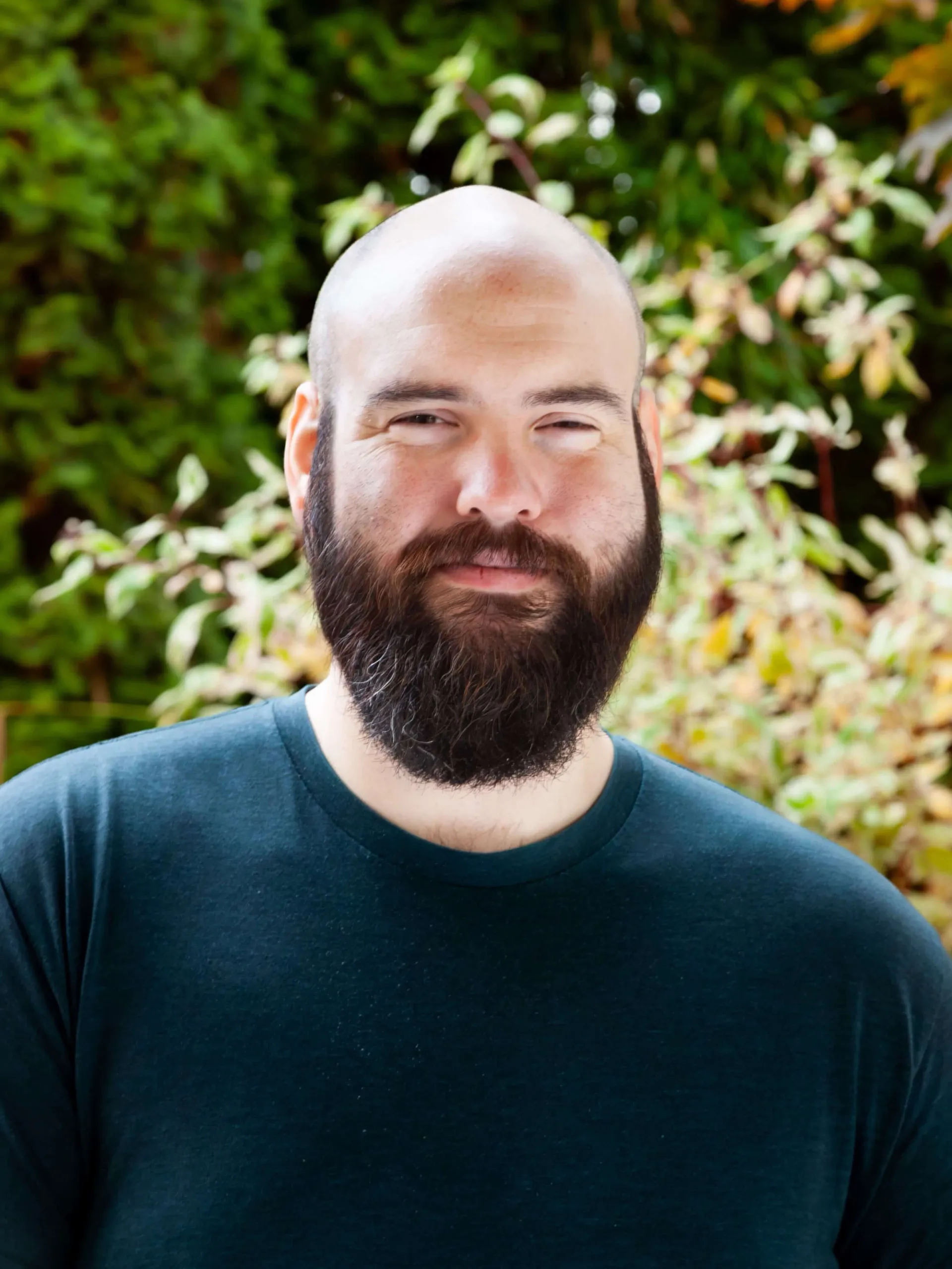 Man smiling with a bald head and large beard.