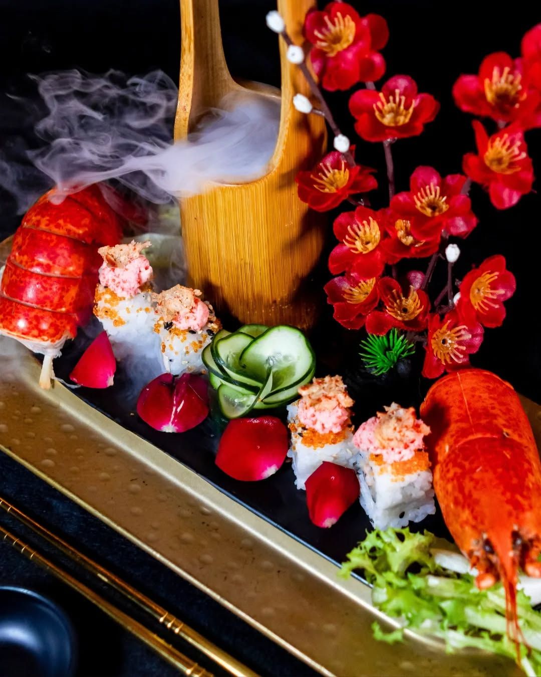 Composizione di sushi servita con scenografia di fumo e astice