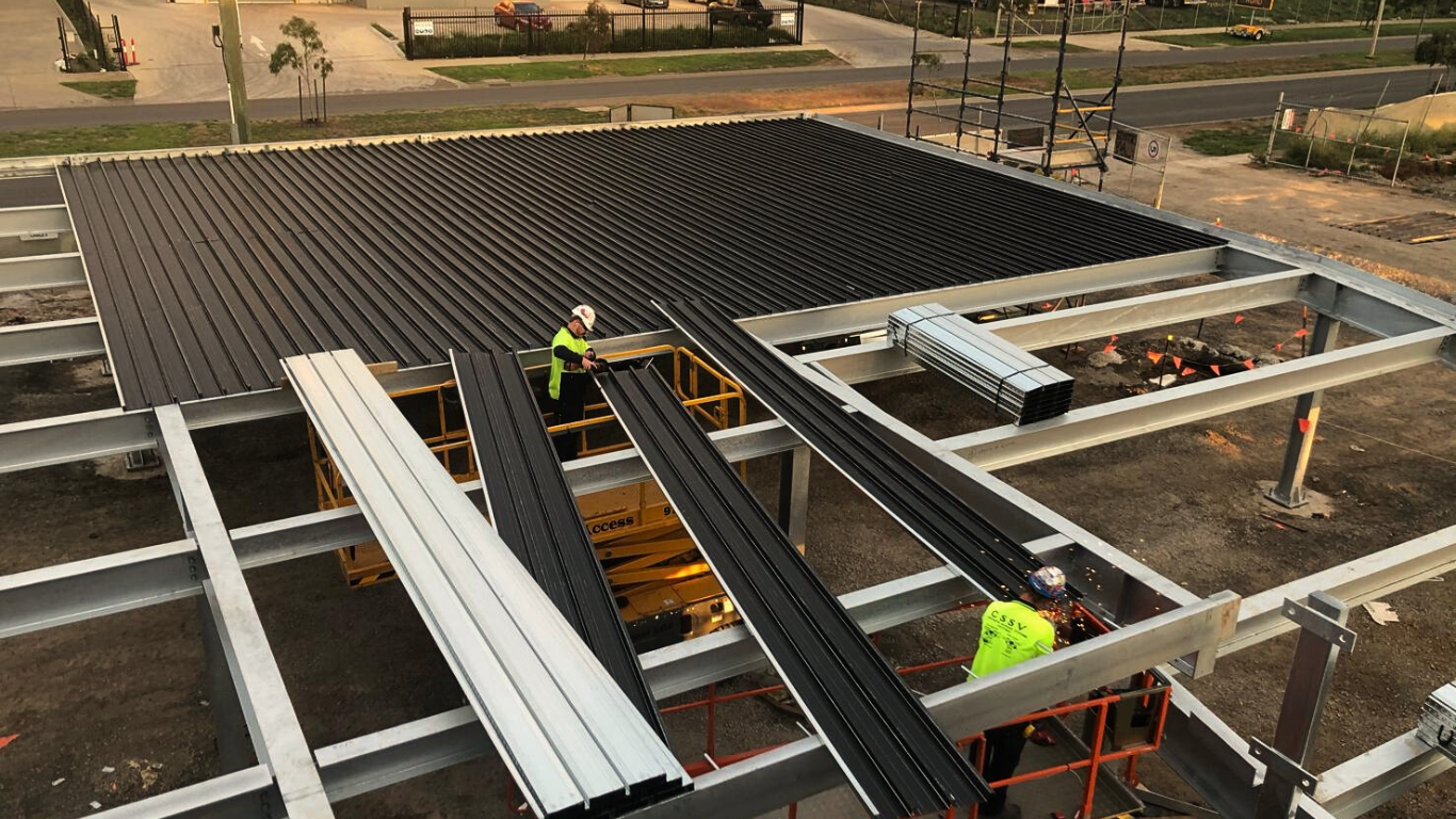 A group of construction workers are working on the roof of a building.