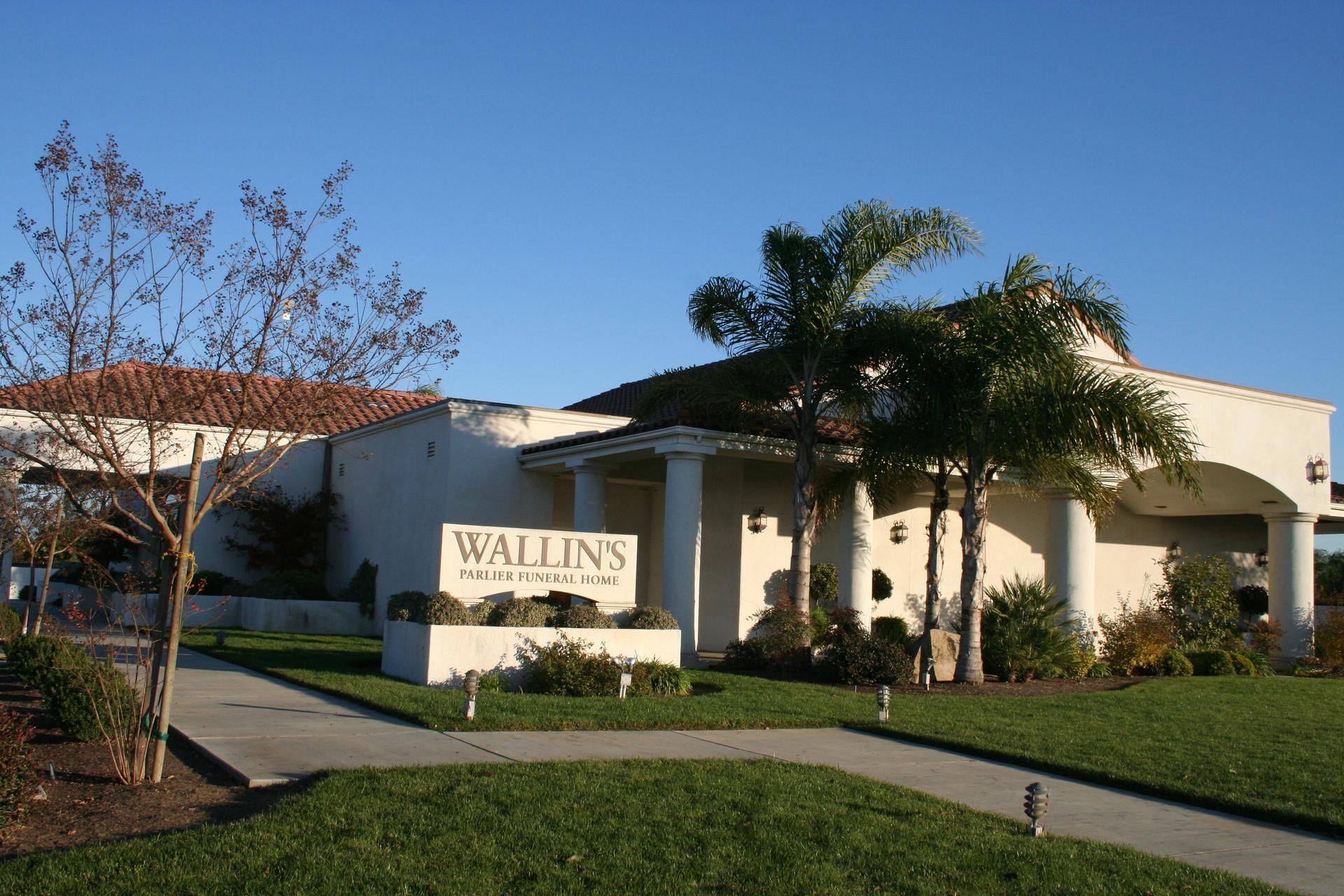 Walzins sign outside a stucco building with palm trees and a manicured lawn