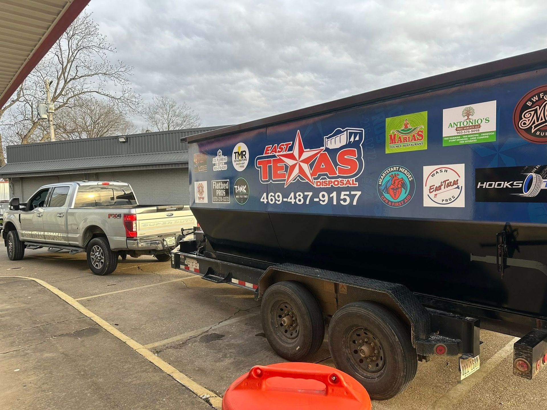 Black Texas-branded trailer hitched to a pickup truck in a parking lot.