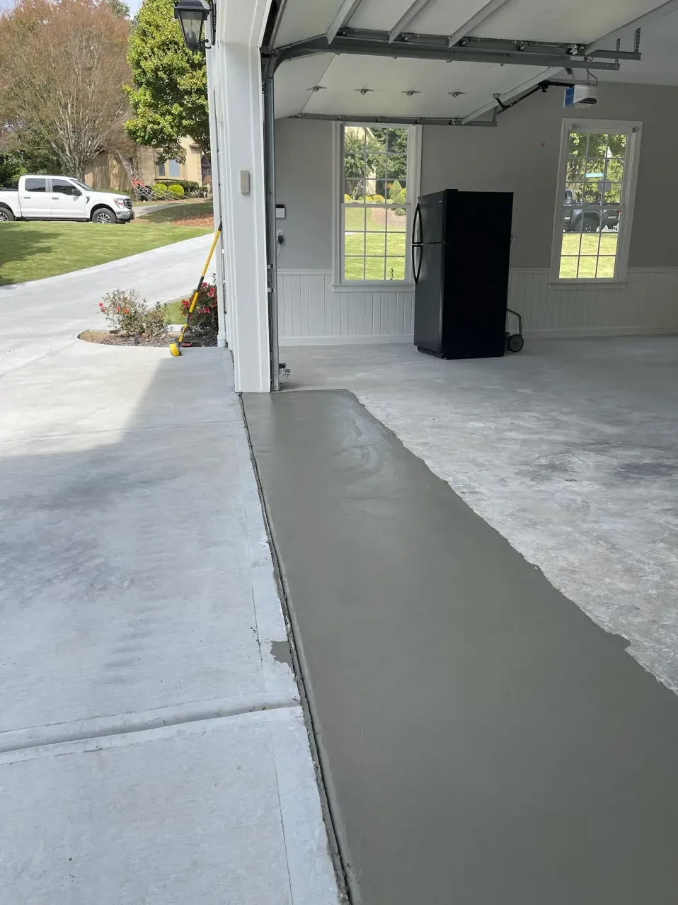 A new, smooth strip of poured concrete patches the entrance to a garage, creating a level transition to the driveway.