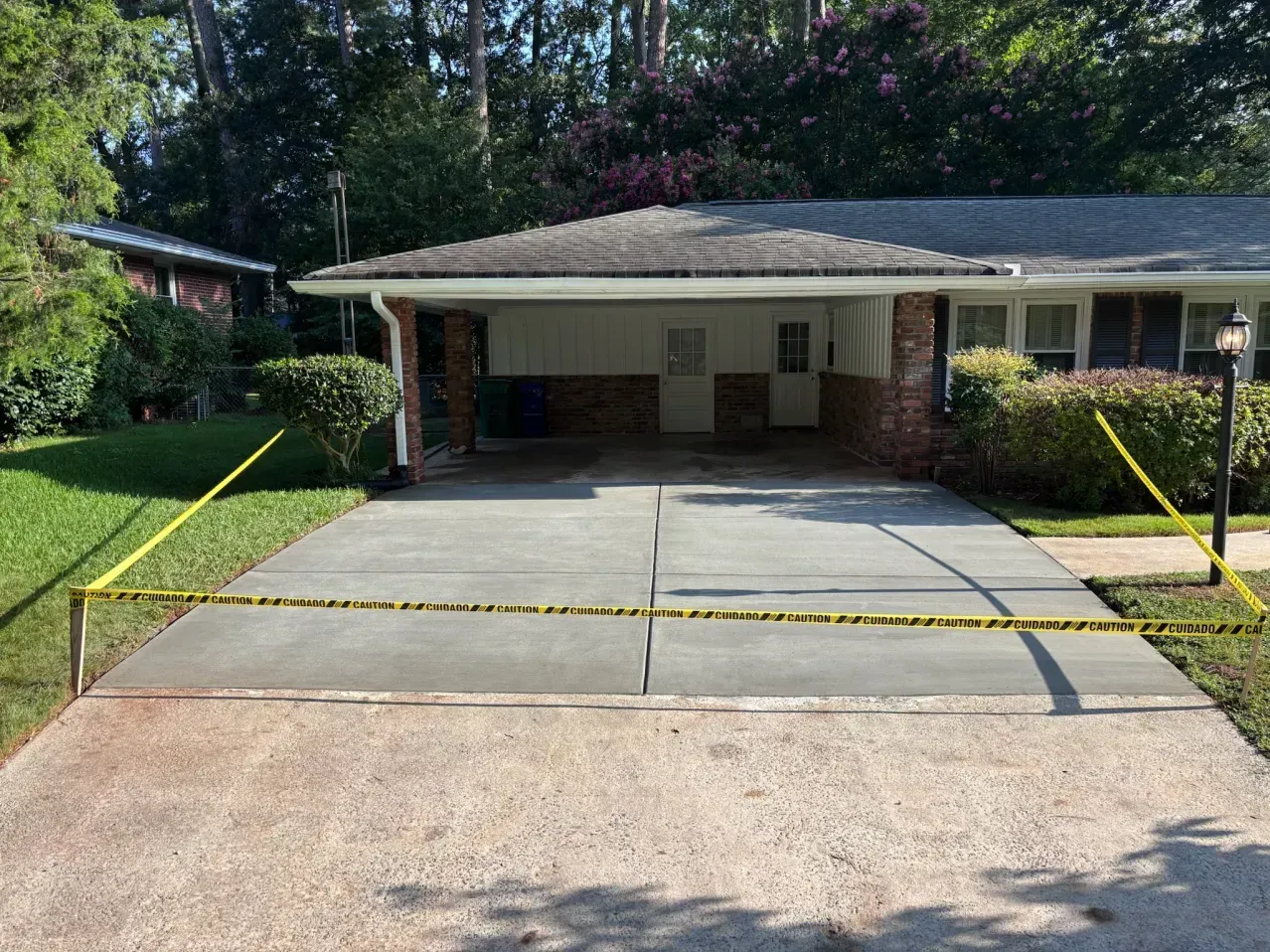 Single-story house with a wide concrete driveway, carport, and green lawn