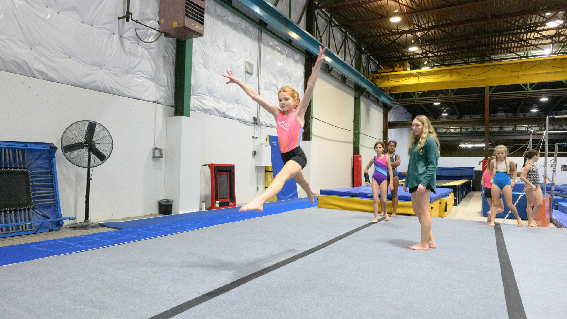 Pre-team gymnast leaping across the gym floor
