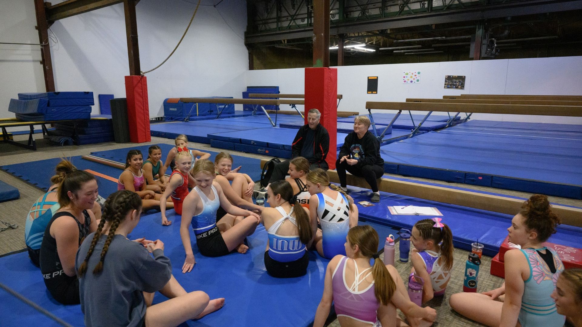 Team gymnasts sitting on the mat during practice