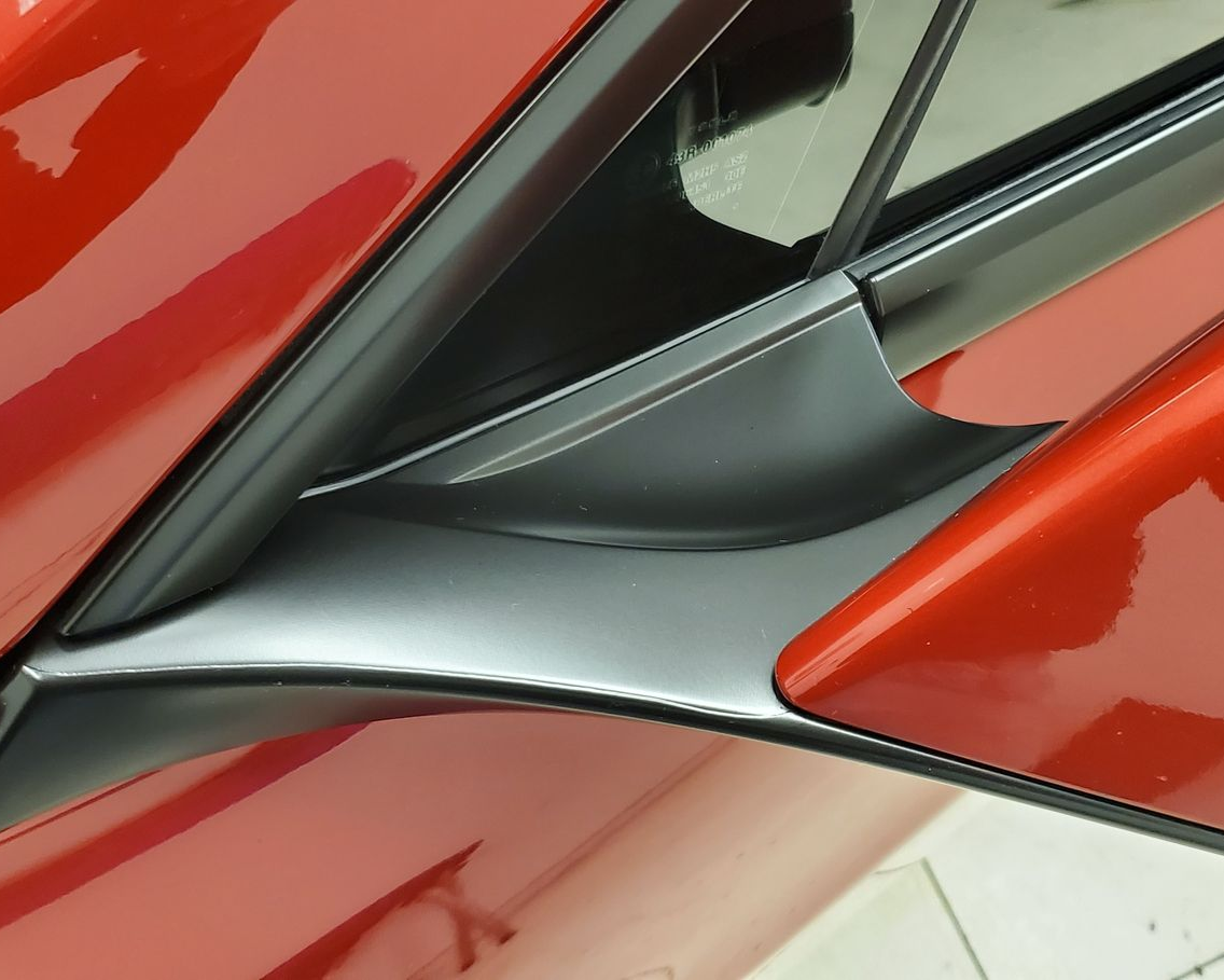 Red car's body with black trim and a reflective surface.