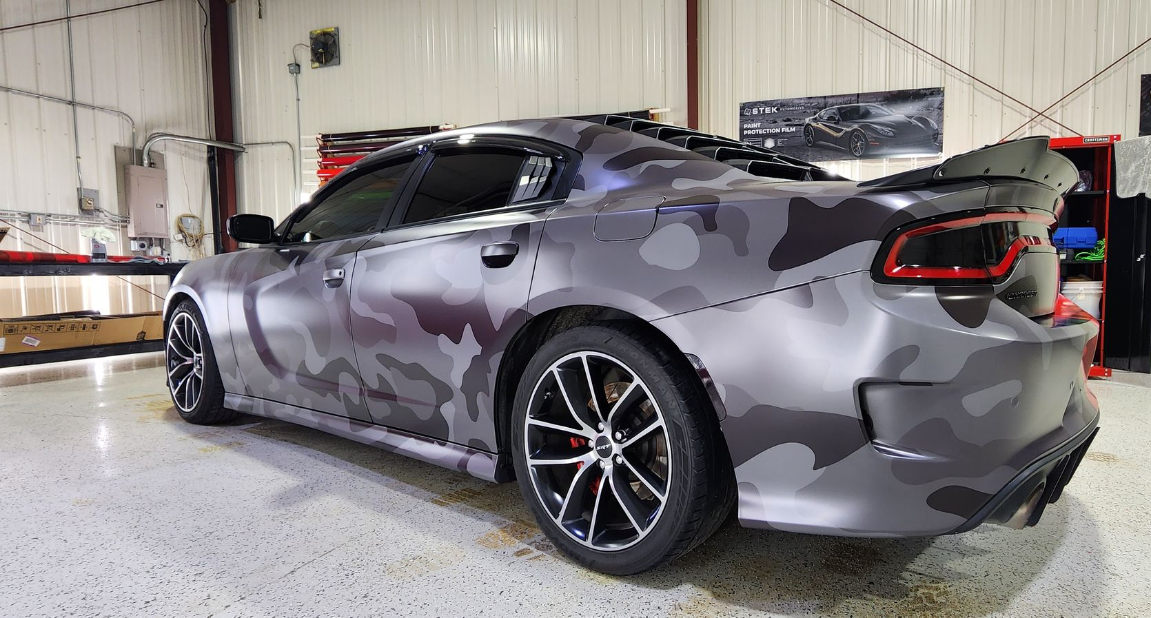 Gray camo Dodge Charger in a garage.
