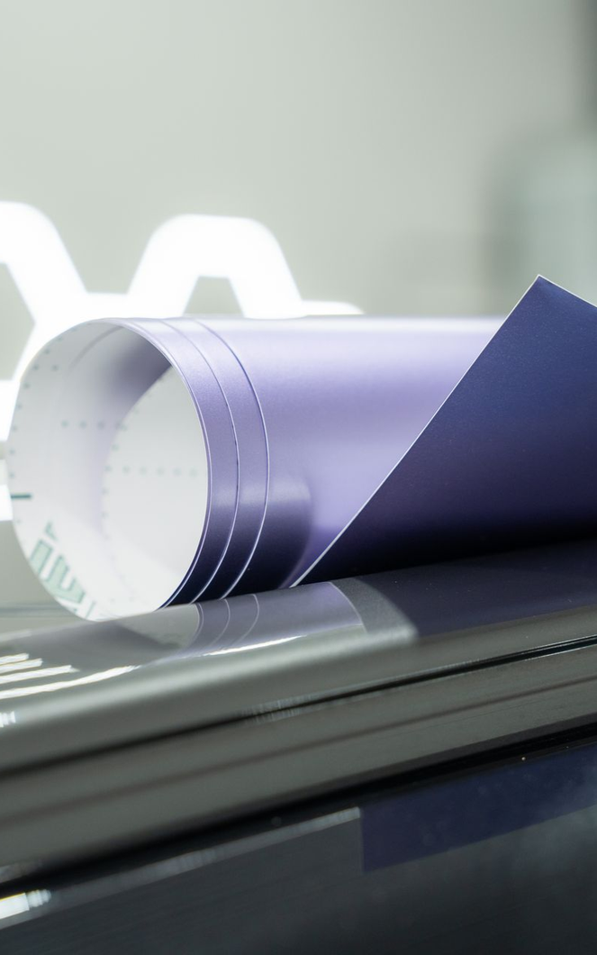 Rolled blue vinyl sheet resting on a stack of gray objects.