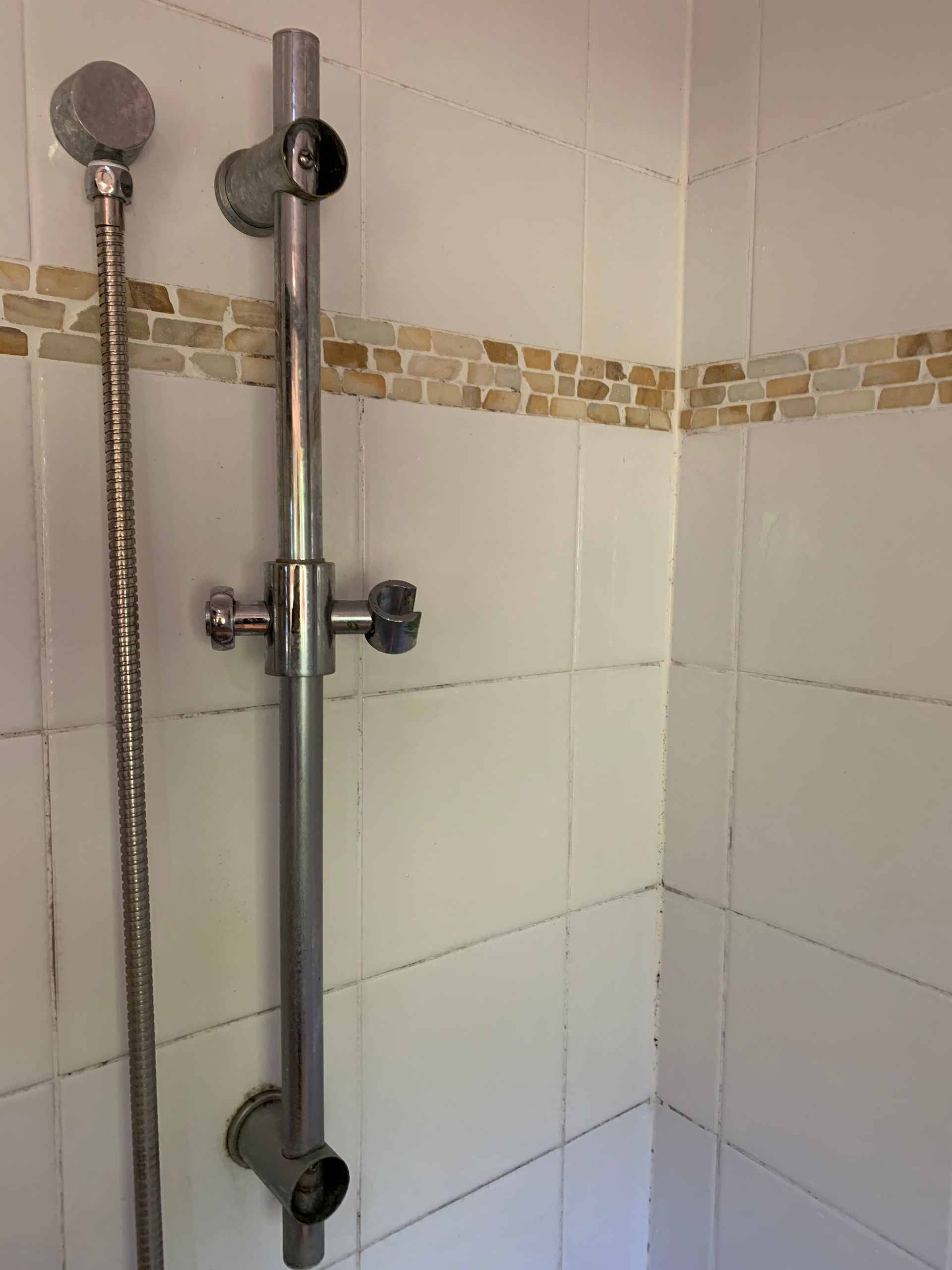 A shower mount and hose in a bathroom corner — Delaney Plumbing Services In Old Bar, NSW