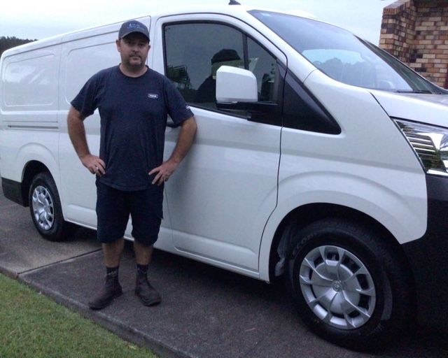 A shower head and mount in a tiled bathroom corner — Delaney Plumbing Services In Wingham, NSW