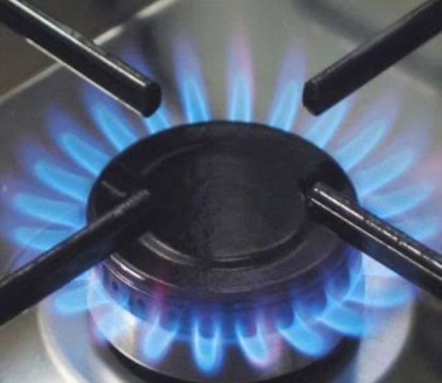 A close up of a gas bottle with copper hoses and the pressure valves connected to a wall — Delaney Plumbing Services In Taree, NSW