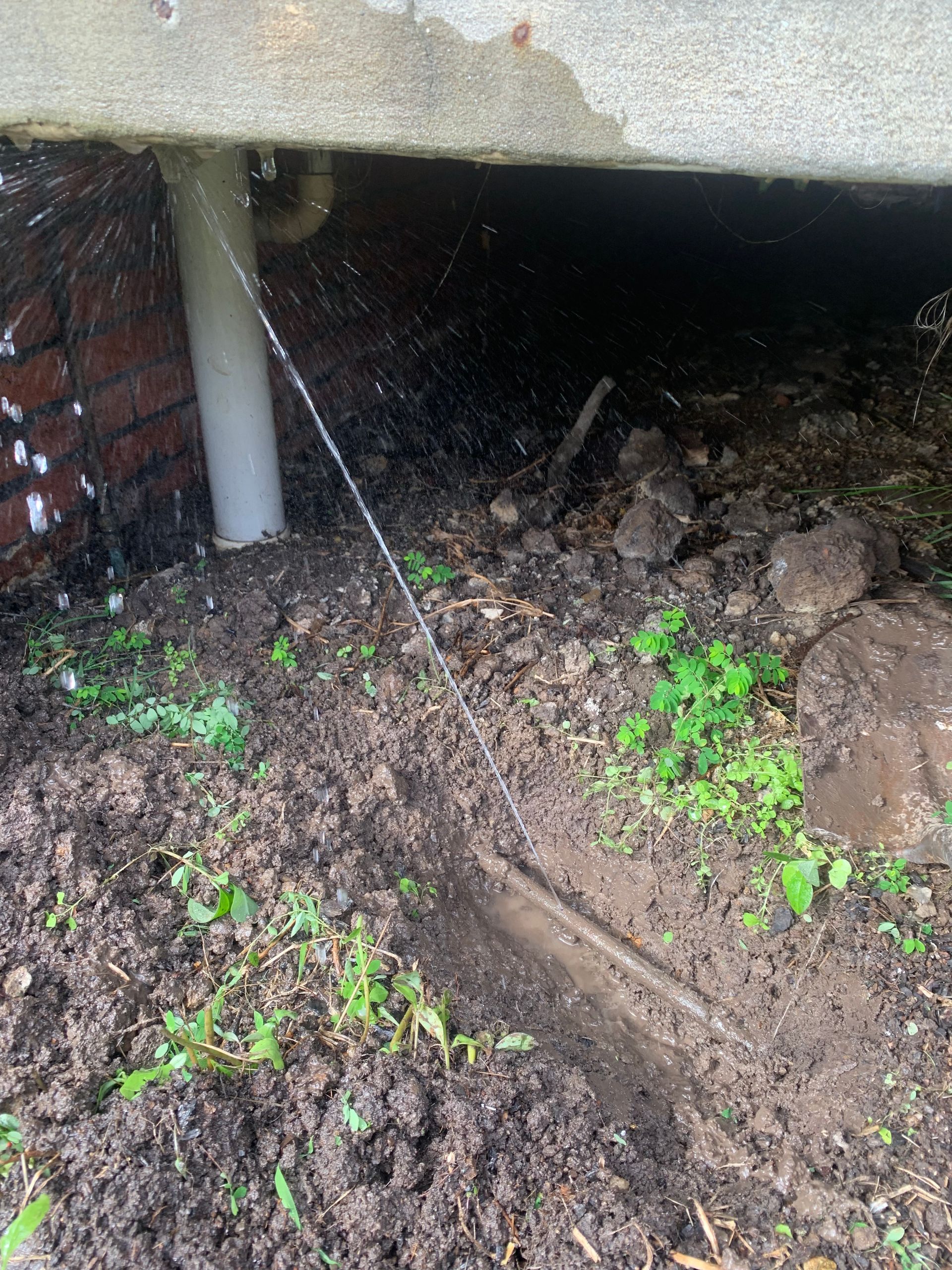 a leaky pipe splashing water on a muddy surface outside — Delaney Plumbing Services In Taree, NSW
