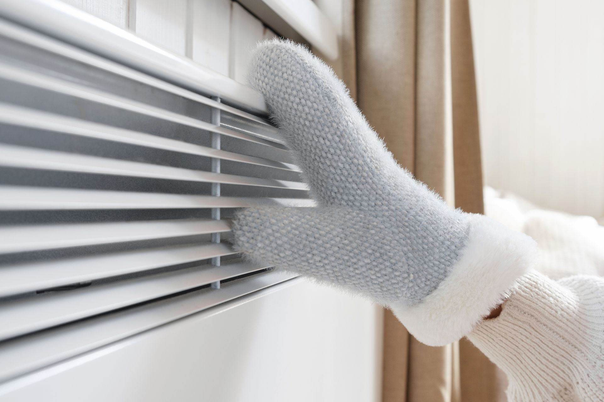A person wearing gloves is warming their feet on a radiator.