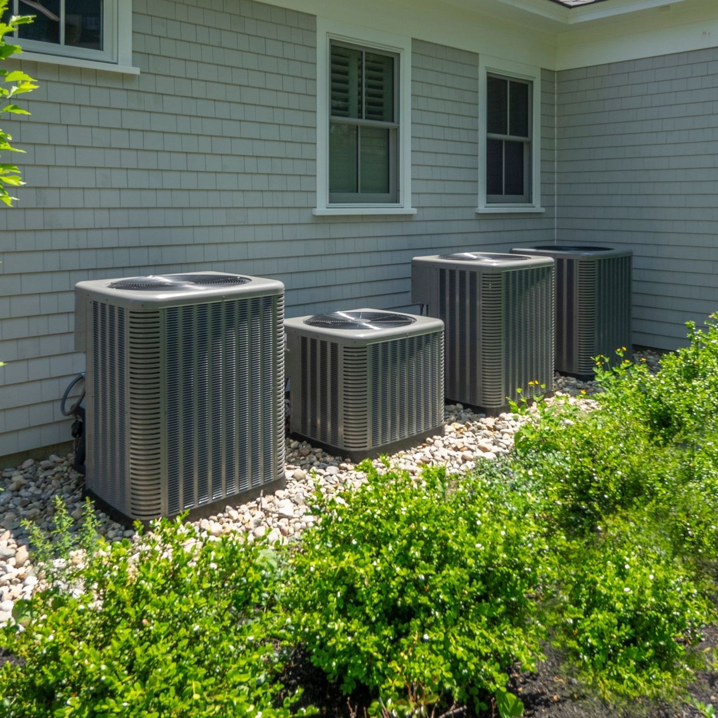 A row of air conditioners outside of a house.