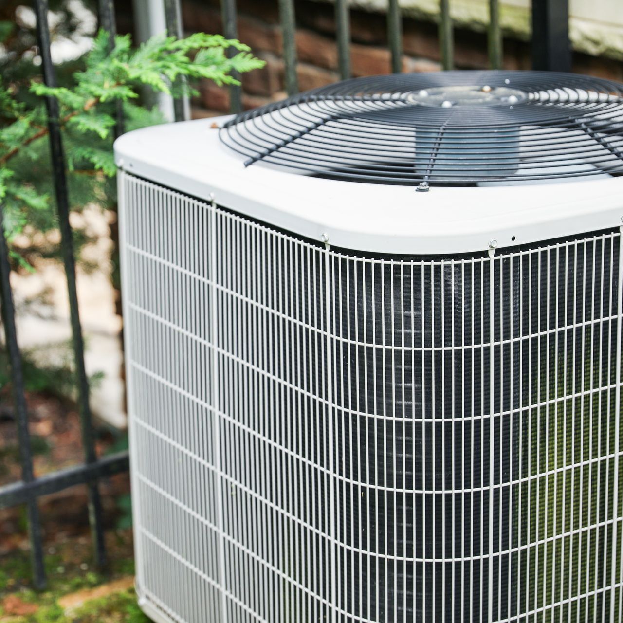 A close up of an air conditioner sitting next to a fence.