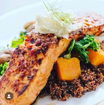 Pan-seared salmon with quinoa, butternut squash, kale, and cream topping.