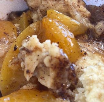 Close-up of peach cobbler, with golden peaches and crumbly topping.