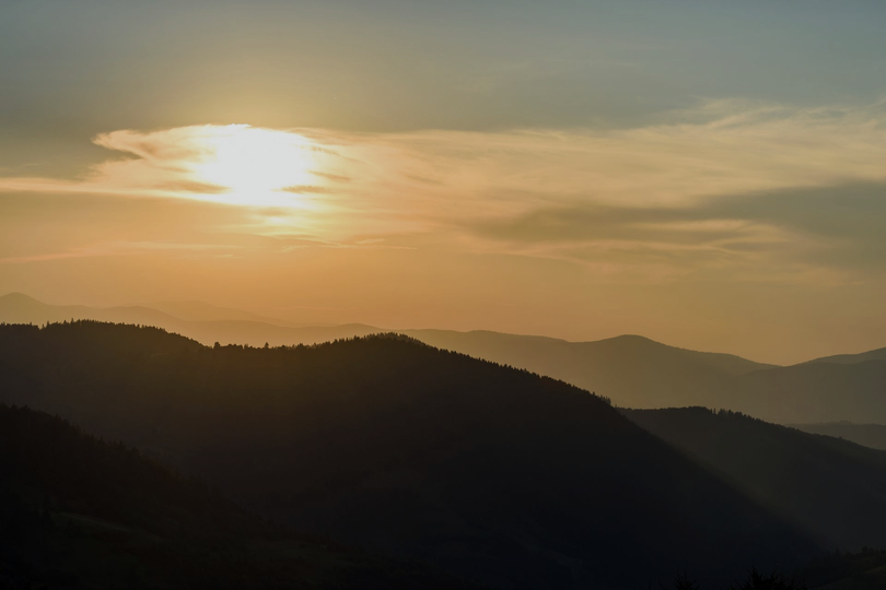 Sunrise over layered mountain ridges with a golden sky