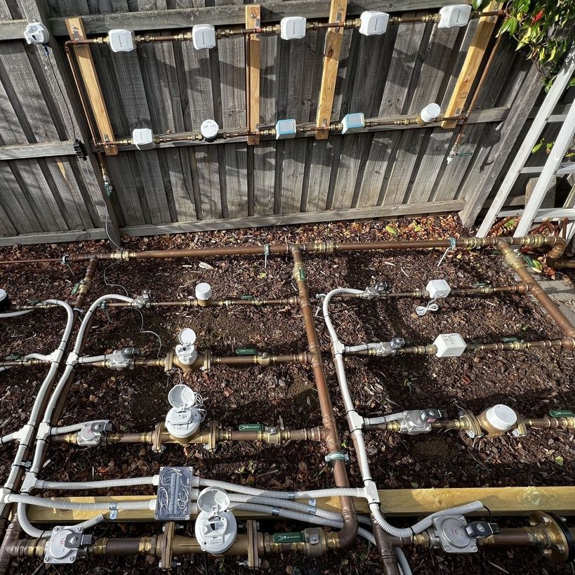 Row of gas meters with black pipes mounted on a beige exterior wall