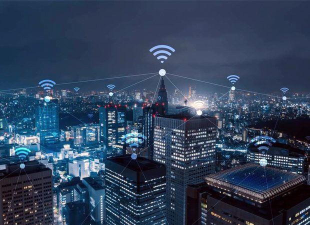 Night city skyline with glowing wireless signal icons above skyscrapers at dusk