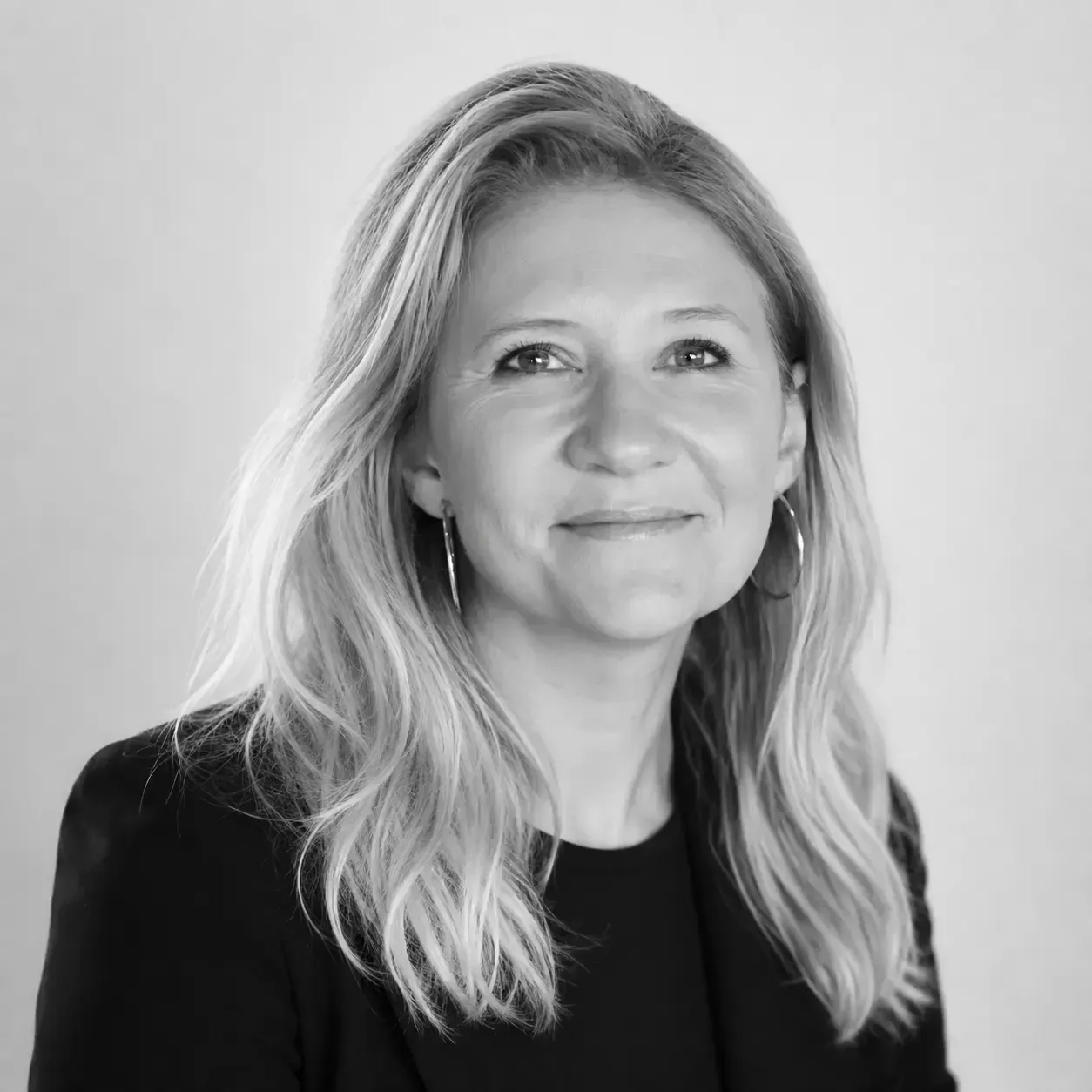 Black-and-white portrait of a smiling woman with long blonde hair against a plain background