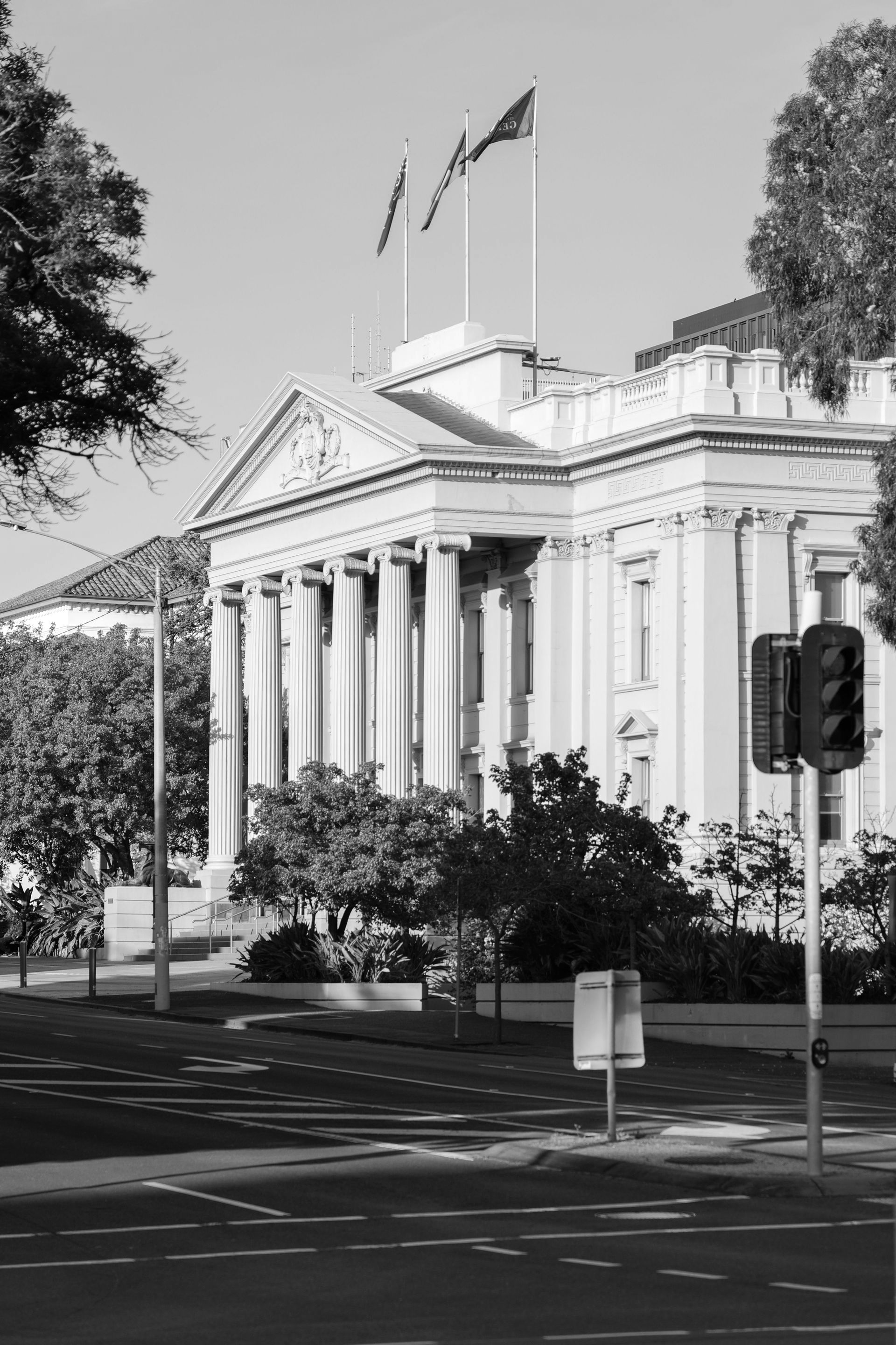 Neoclassical building with columns and flags beside a quiet street on a sunny day