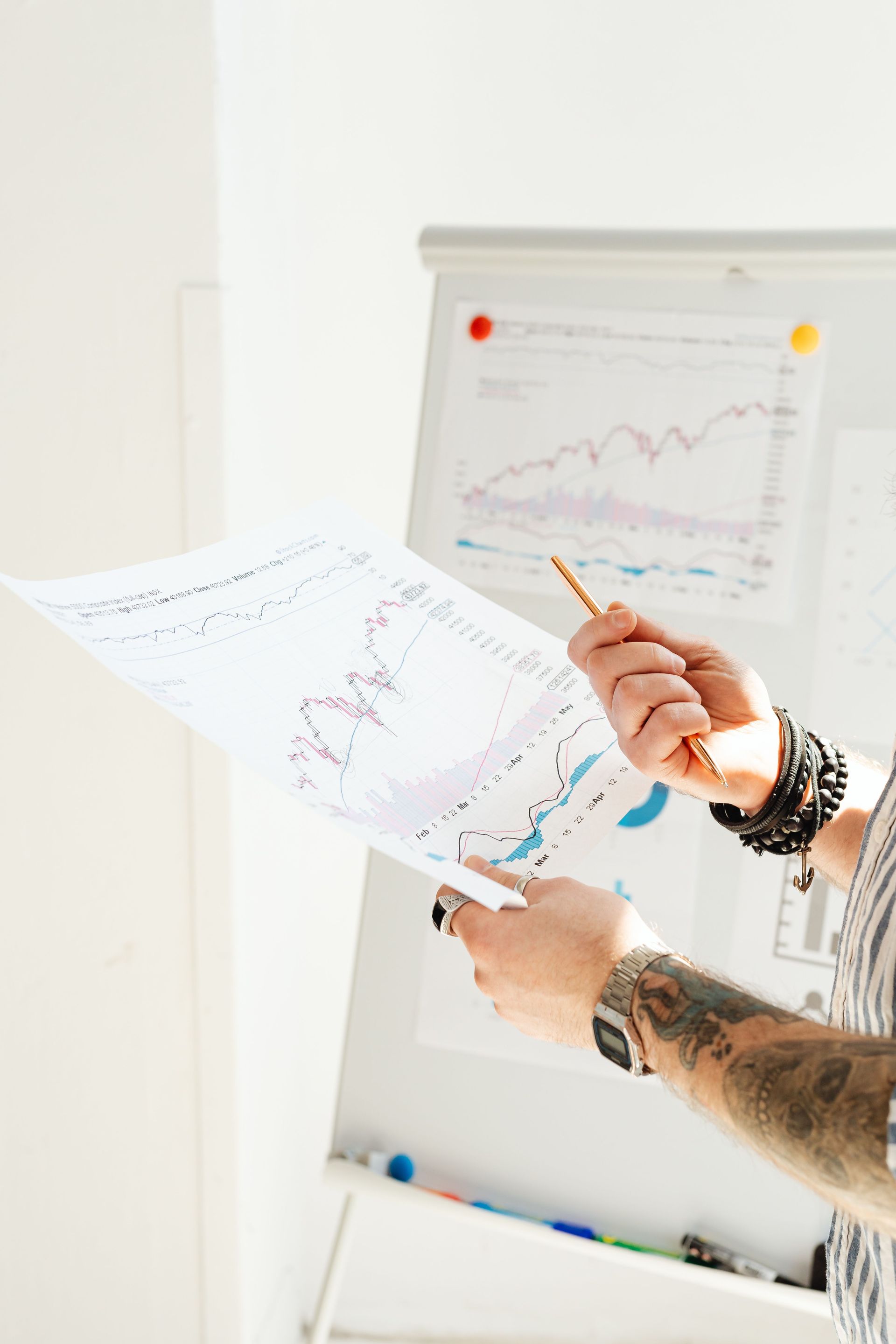 Person pointing at charts on a whiteboard during a meeting