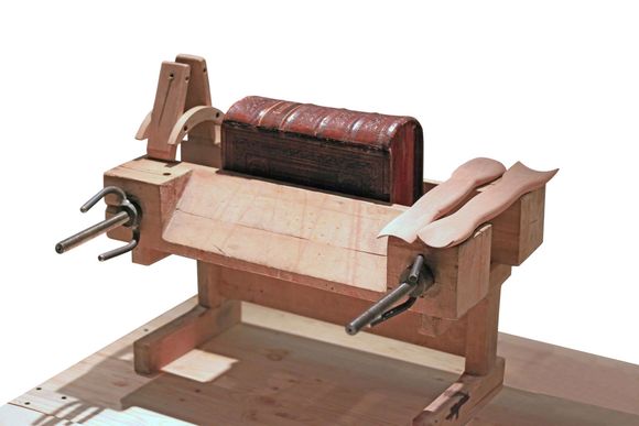 Torchio per legatoria in legno con un libro inserito, pronto per l'uso.