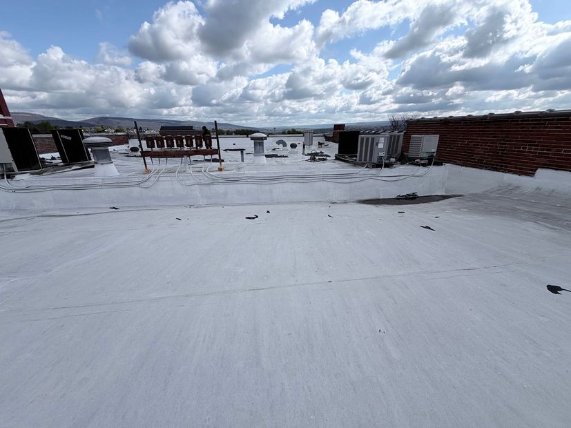 Snow-covered rooftop under a cloudy sky, with low buildings and distant trees on the horizon.