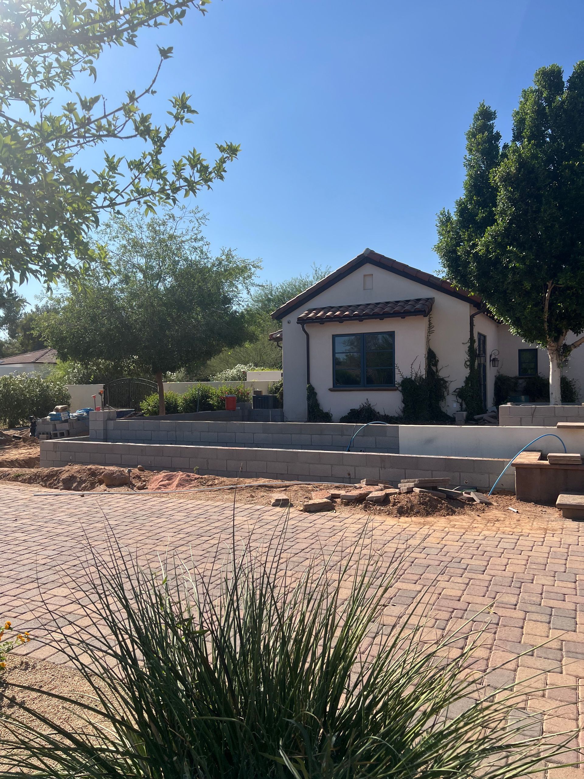 Small stucco house with a tiled roof and porch, framed by trees and a dry landscaped front yard.