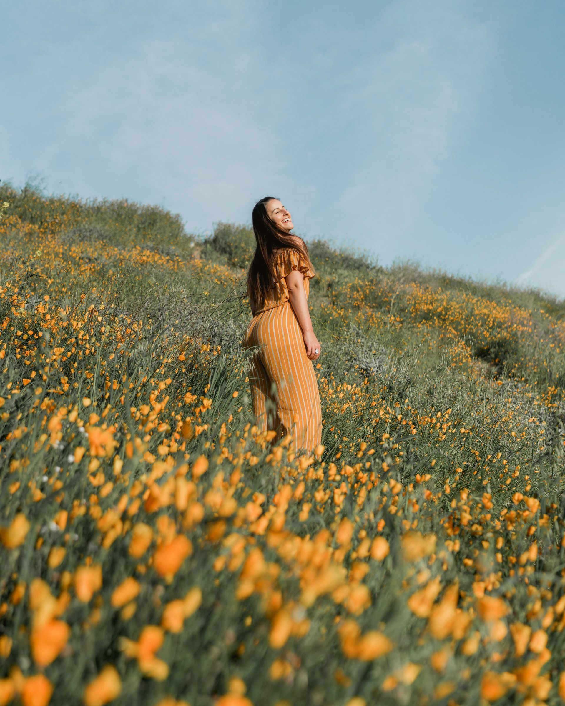 Woman standing in a yellow wildflower field under a blue sky