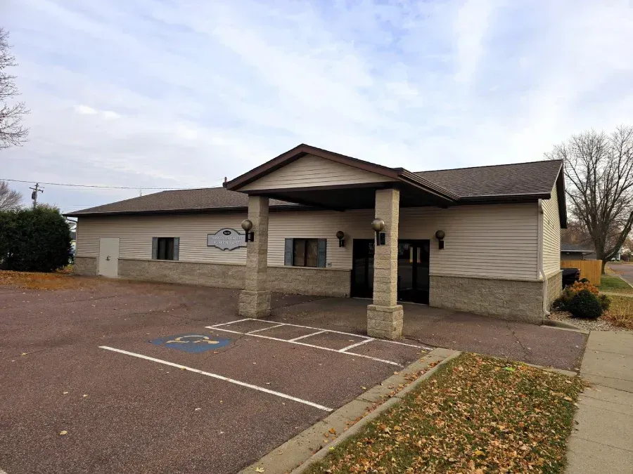 A tan single-story building with a stone-accented facade, a front entrance portico, and a handicap parking space.