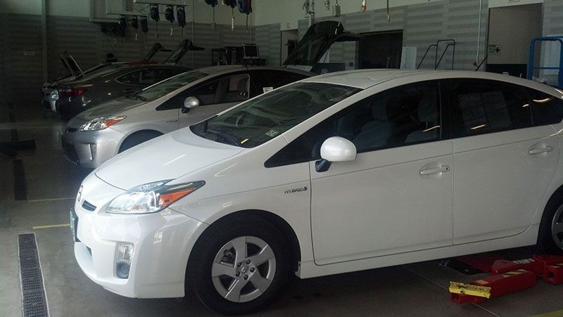 A row of white prius cars are parked in a garage | Autotrends