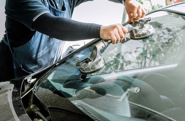 A man is installing a windshield on a car | Autotrends