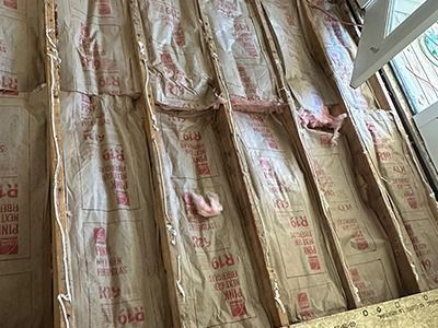 Fiberglass insulation batting installed between wooden ceiling or floor joists.