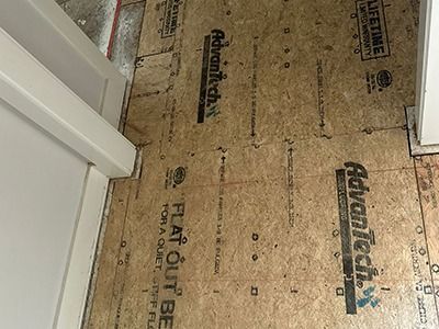 An overhead view of Advantech subflooring panels installed on a floor next to a white door frame and wall.