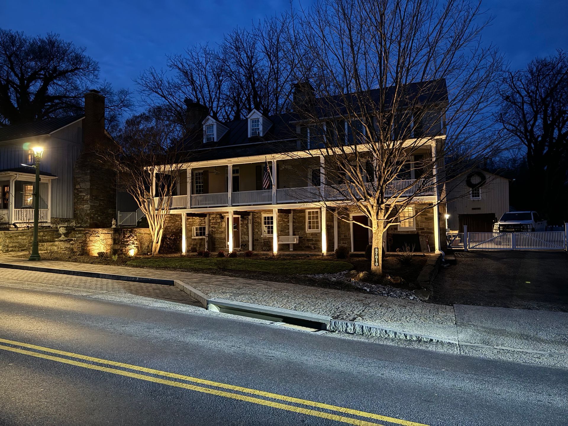 A large house with a porch is lit up at night.