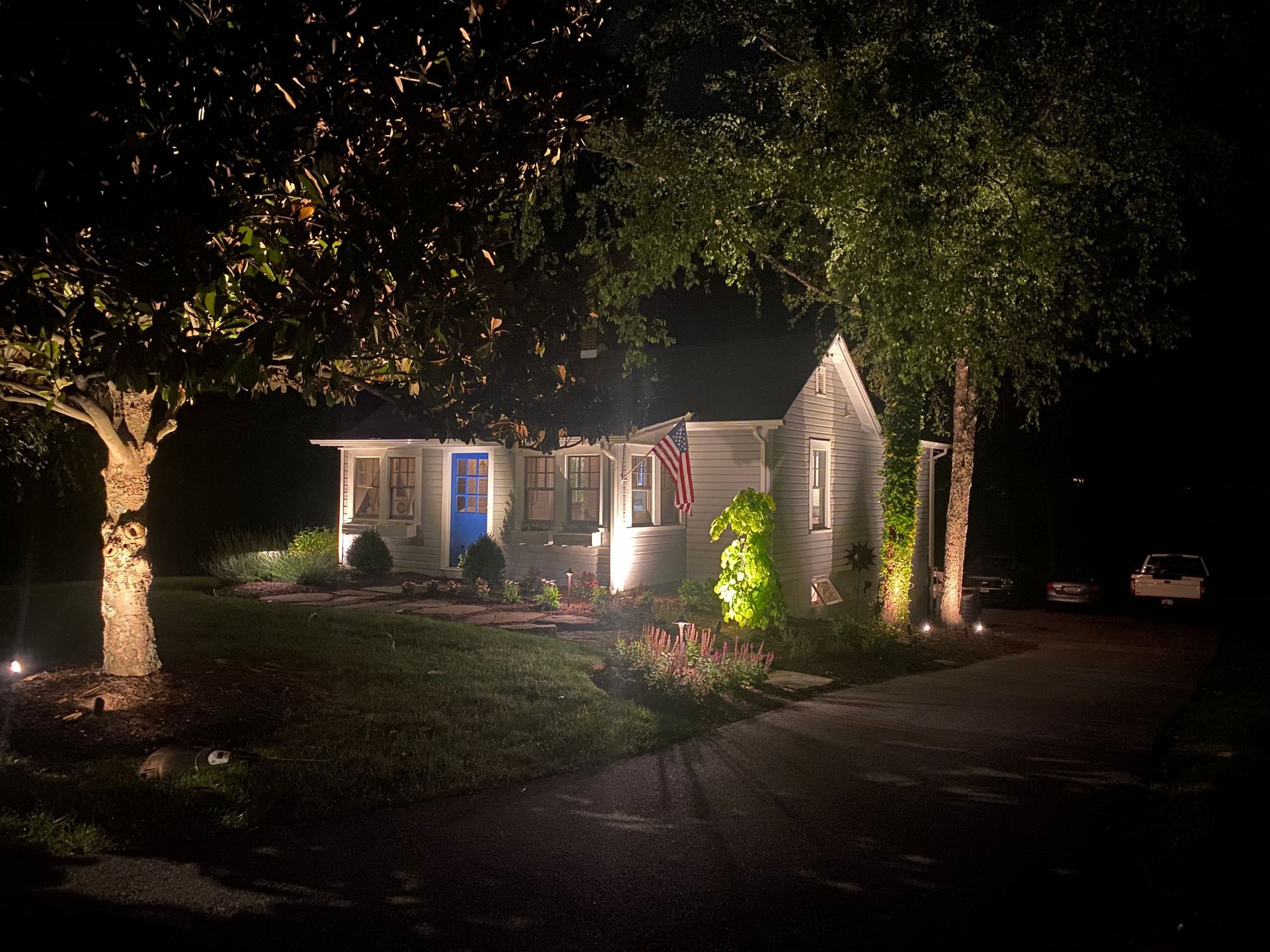 A house is lit up at night with trees in front of it.