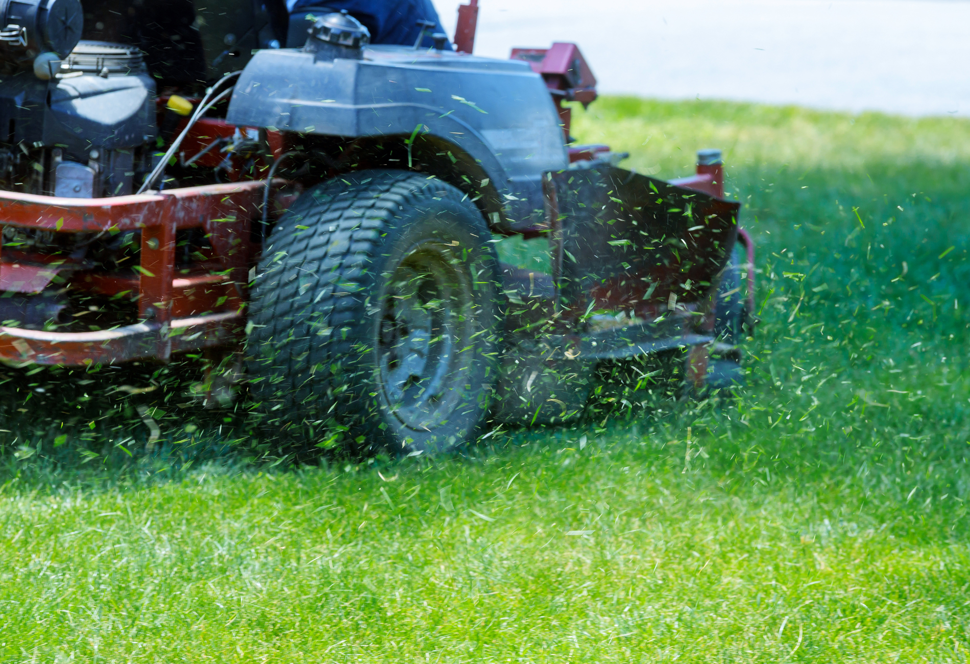 A man is riding a lawn mower on a lush green lawn.