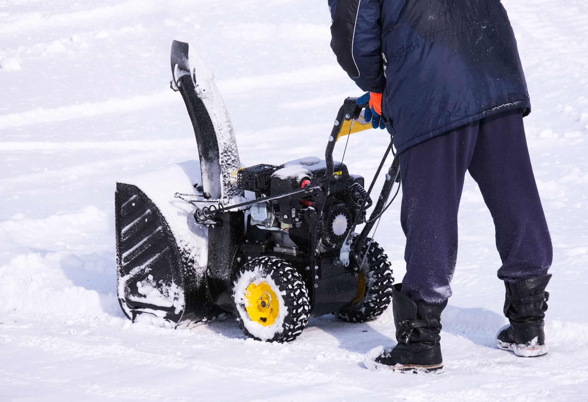 A man is using a snow blower to clear snow from his driveway.