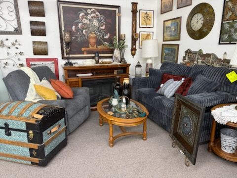 Cozy living room with two gray sofas, a coffee table, chest, and wall art around a fireplace.